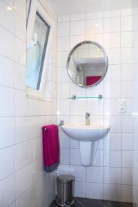 une salle de bain blanche avec un lavabo et un miroir dans l'établissement Ferienwohnungen Moselterrasse, à Detzem