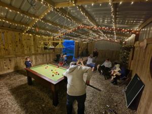 a man swinging a bat at a pool table at Beautiful 1-Bed bell tent in Holyhead in Holyhead