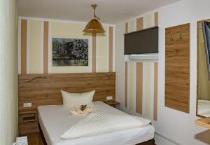 um pequeno quarto com uma cama com lençóis brancos em Hotel Zum Stern Spreewald em Werben