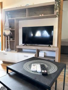 sala de estar con TV y mesa con mando a distancia en Apartmani M.&.B Luks en Mataruška Banja