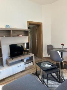 a living room with a flat screen tv and a table at Apartmani M.&.B Luks in Mataruška Banja