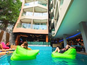 a group of people sitting on inflatable chairs in a swimming pool at Mad Monkey Phuket in Patong Beach