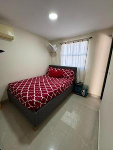 een slaapkamer met een bed met een rood dekbed en een raam bij Hospedaje Dino in Cartagena