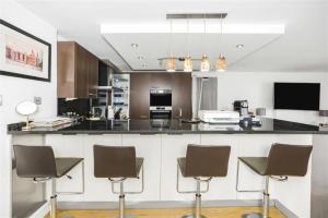 a kitchen with a bar with four chairs in it at Subpenthouse sleeps 6, Stunning views of Tower Bridge! in London