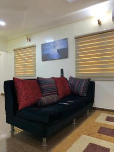 a black couch with pillows in a living room at Comfortable 2BDR Apt - Superb power supply, Wi-Fi, Kitchen, Netflix, Mins to Airport in Agege