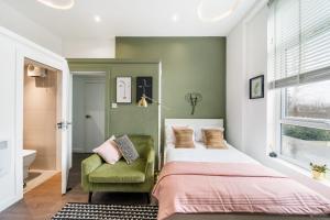 a bedroom with a bed and a green chair at Stunning studio flats in Penge in Sydenham