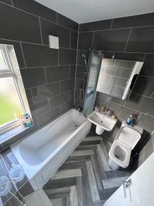 uma casa de banho com uma banheira, um WC e um lavatório. em Glo Stay @ Hibbert Crescent em Skegby