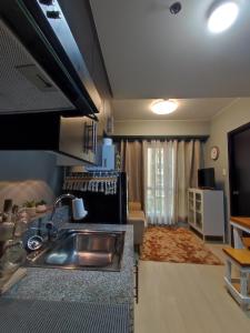 eine Küche mit einem Waschbecken und ein Wohnzimmer in der Unterkunft RC Staycation in Manila