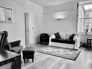 a black and white living room with a couch and chairs at St Andrews Apartments in Maidstone