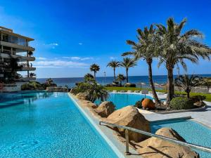 - une piscine dans un complexe avec des palmiers et l'océan dans l'établissement Mascarat Beach Apartment de Lux, EN52B, à Altea la Vieja
