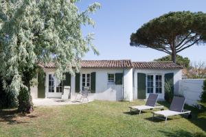 a house with two chairs in the yard at LATITUDE46 maison de charme à Sainte Marie de Ré in La Noue