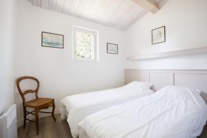 ein weißes Schlafzimmer mit 2 Betten und einem Stuhl in der Unterkunft LATITUDE46 maison de charme à Sainte Marie de Ré in La Noue