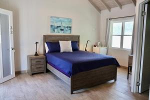 a bedroom with a bed with blue sheets and a window at The Moxy in English Harbour Town