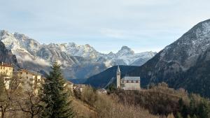 ヴァッレ・ディ・カドーレにあるIl Quadrifoglio - alloggio turisticoの山を背景に建つ丘の上の教会