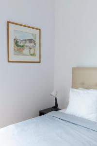 a bedroom with a white bed with a picture on the wall at Olympic Hadrian view apartment! in Athens