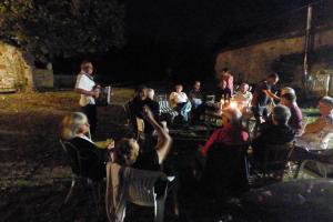 um grupo de pessoas sentadas em cadeiras à noite em Domaine de la Borde em Puy-lʼÉvêque