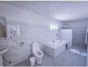 a white bathroom with a toilet and a tub and a sink at TAKAWIRI VICTORIA SANDS 