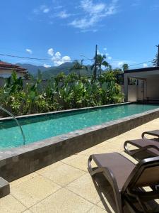 a swimming pool with two lawn chairs next to it at Pousada Yamandu in Juquei