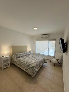 1 dormitorio con cama, ventana y silla en Casa de playa en Balneario Claromecó