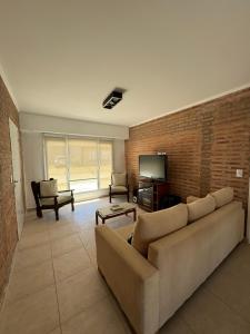 sala de estar con sofá y pared de ladrillo en Casa de playa en Balneario Claromecó