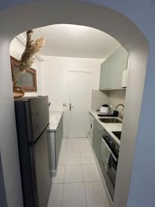 een keuken met een boog, een koelkast en een fornuis bij Studio purple proche Paris in Chennevières-sur-Marne +6 foto's