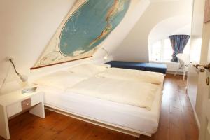 ein Schlafzimmer mit einem weißen Bett und einem großen Gemälde an der Wand in der Unterkunft Wattwanderer in Oldsum