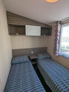two beds in a small room with a window at Relaxing Holiday Home Chickerell View Littlesea Haven in Weymouth
