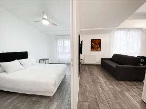 1 dormitorio con cama blanca y sofá negro en Résidence 4T IMMO - 31 Avenue Gaston Chauvin en Aulnay-sous-Bois