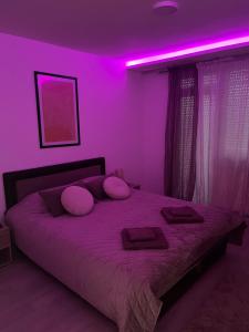 a bedroom with a bed with purple lights on it at Apartman Rose in Kruševac