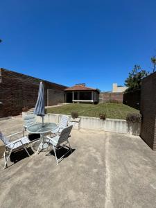 un patio con mesa, sillas y sombrilla en Casa de playa en Balneario Claromecó