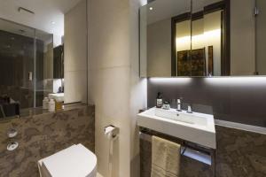 a bathroom with a sink and a toilet and a mirror at Subpenthouse sleeps 6, Stunning views of Tower Bridge! in London