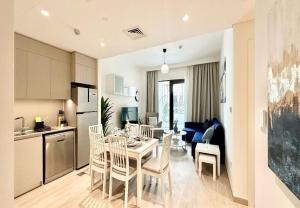 EasyGo - Sunset Creek 1 Bedroom في دبي: مطبخ وغرفة طعام مع طاولة وكراسي