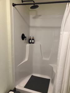 a white bathroom with a shower with two bottles on it at Prairie Rose Inn in WaKeeney