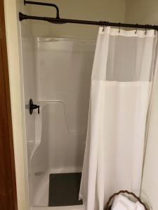 a shower with a white shower curtain in a bathroom at Prairie Rose Inn in WaKeeney