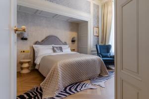 a bedroom with a bed and a blue chair at Hotel Unicus Palace Old Town - Destigo Hotels in Krakow