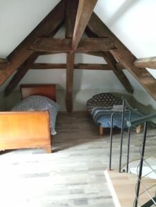 a attic room with two beds and wooden beams at Maison calme in Vinzelles