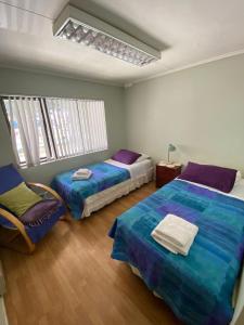 Un dormitorio con 2 camas y una silla. en Karol Hostal, en Punta Arenas