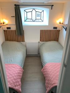 two beds in a small room with a window at Logeerboerderij de Salix in Hitzum