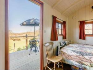 a bedroom with a bed and a balcony with an umbrella at Pooks Rest in Hurst Green
