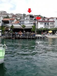 um restaurante na água com edifícios ao fundo em Orhidea House em Ohrid