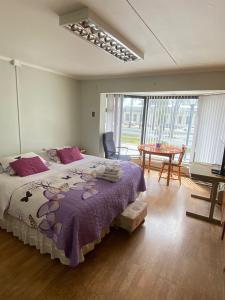 1 dormitorio con 1 cama grande con manta morada en Karol Hostal, en Punta Arenas