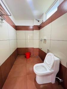a bathroom with a toilet and a red bucket at Queen-C Inn in Mānantoddy