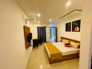 1 dormitorio con 1 cama y TV. en Queen-C Inn, en Mānantoddy