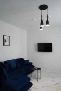 uma sala de estar com um sofá azul e uma televisão em Апарт-готель LOGOS em Skhidnitsa