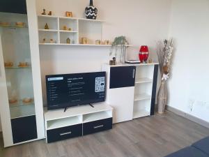 sala de estar con TV y estanterías blancas en San Clemente with Pool & Wi-fi, en Caleta de Interián