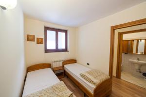 two beds in a room with a sink and a mirror at Residence Stofol in Aprica