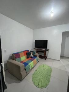 een woonkamer met een bank en een televisie bij Casa02 - Mariscal/Canto Grande a 150mts da praia in Bombinhas