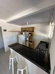 een keuken met een zwart aanrecht en 2 krukken bij Casa02 - Mariscal/Canto Grande a 150mts da praia in Bombinhas