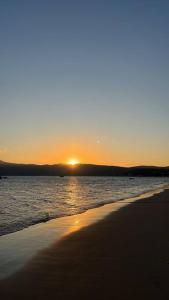 een zonsondergang op een strand met zonsondergang in de verte bij Casa02 - Mariscal/Canto Grande a 150mts da praia in Bombinhas