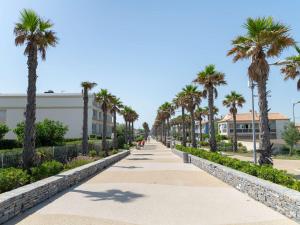 un marciapiede fiancheggiato da palme di fronte a un edificio di Appartement Marseillan-Plage, 3 pièces, 6 personnes - FR-1-387-158 a Marseillan